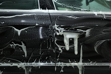 Wall Mural - car washing close-up. part of car is in foam at the car wash