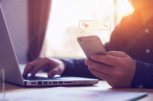 Fotografía Close up businessman using laptop holding mobile smart phone, using device to co