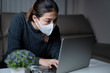 © Poomsak - Asian woman working from home overtime. Asian businesswoman remote working while sitting on the sofa in living room. Young adult Asian beautiful woman using laptop at night.