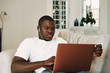 © SHOTPRIME STUDIO - A man of African appearance at home in front of a laptop relaxing