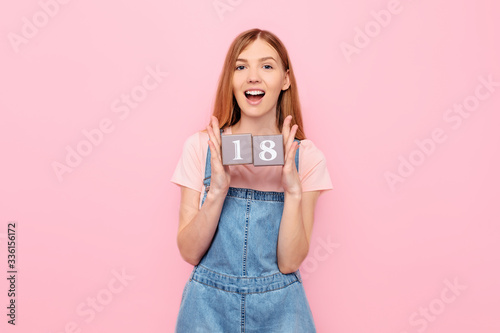 Fotomural young woman is celebrating her birthday and holding cubes with her age 18 eighte