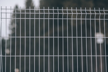 White fence made of thin metal rods. Barrier texture metal fence