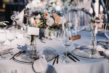 Wedding decor in blue and gray. Banquet tables with tablecloths are decorated with compositions of flowers, on the tables are plates, glasses and candles