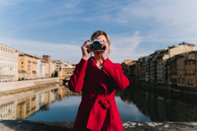 Young Woman Taking A Picture On A Bridge Above River Arno, Florence, Italy