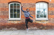 © Westend61 - Young man jumping in front of brick wall