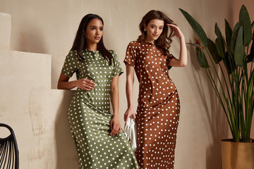 Two fashion model brunette hair wear green  brown dots silk dress shoes accessory clothes date party walk interior journey summer collection plant flowerpot stairs beautiful woman tan skin friends.