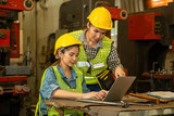 Fototapeta Panele - Industrial engineer in hard hat wearing safety using laptop for planning a project at factory site.