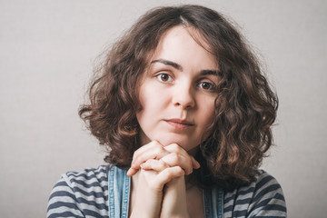 The woman folded her hands in prayer. Gray background