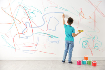 Sticker - Little child drawing scribbles on white wall indoors