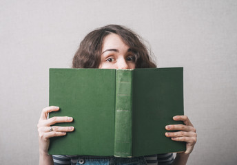 girl with big book in hand in hand on a gray background