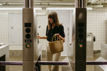 Young Woman With Bangs Smiling Walking Through The Turnstile In A Subway Stop