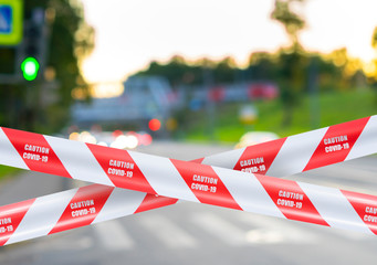 Wall Mural - red and white warning caution tape covid-19 warning over blurred cityscape, quarantine concept, city isolation