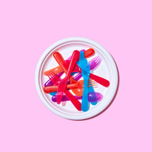 Plastic Knives, Forks, Spoons In A White Plate On A Pink Background