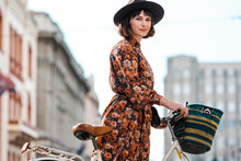 Portrait Of Stylish Woman In Floral Dress With Bicycle In The City