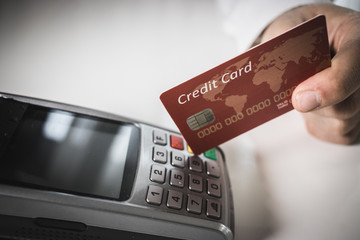 Hand of customer paying with contactless credit card with NFC technology.