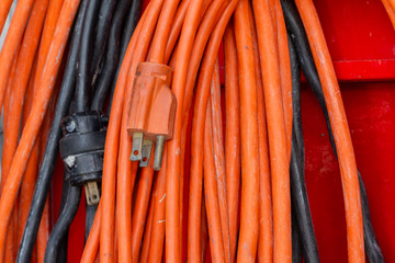 Orange power extension cord with a black one in the background which is blurred. 