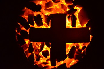 Poster - 
The metal cross lies on the burning coal of a small fraction.