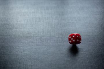 Closeup to a lonely red dice spinning over a black background. Ideal fo gamble, board games and bets