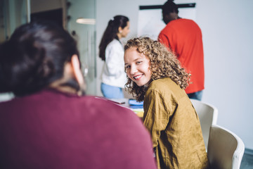 Wall Mural - Joyful confident millennial office worker during meeting with multiracial colleagues in modern conference room