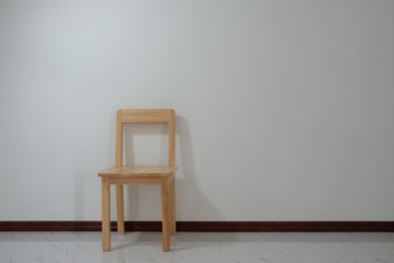 Wooden chair is located in the empty room on the white wall.