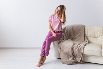 Wall Mural - Young attractive woman dressed in beautiful colorful pajama posing as a model in her living room. Comfortable sleepwear, home relaxation and female fashion concept.