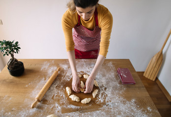 Woman wearing apron prepearing rolls dough for baking. Baking homemade rolls