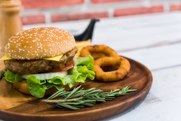 Homemade fresh tasty hamburger side dish with onion fries and rosemary on wood plate with white wooden plank background