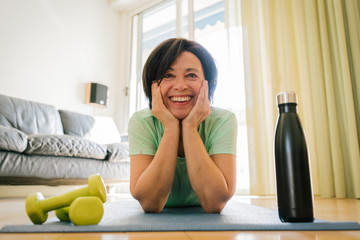 Portrait of a mature woman in sportswear exercising with dumbbells at home. Older female gym in the apartment. Concept about quarantine, gym and sport.