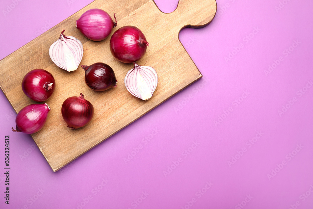 Fresh raw onion and cutting board on color background