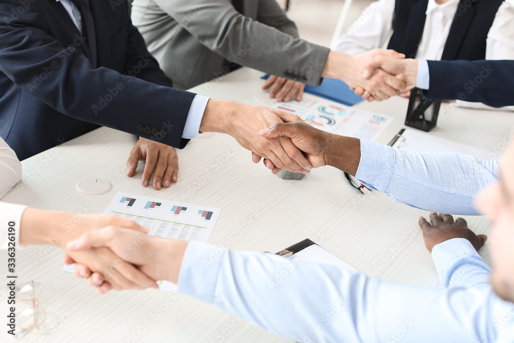 Group of business people holding hands together in office. Unity concept