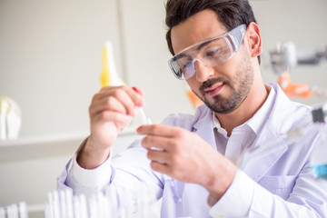 Wall Mural - attractive happiness scientist man lab technician assistant analyzing sample in test tube at laborat
