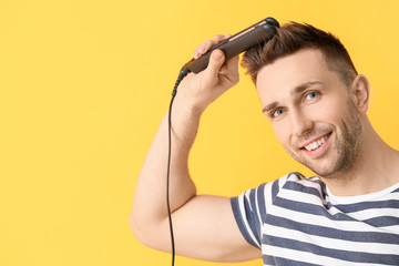 Wall Mural - Handsome young man with flattening iron on color background