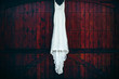 A white wedding dress hanging against a mahogany colored wooden door