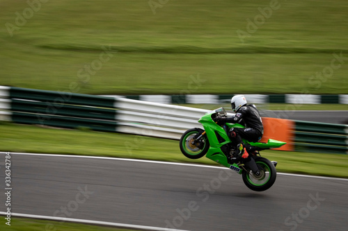 Fotomural A panning image of a green racing bike passing and leaving the ground altogether