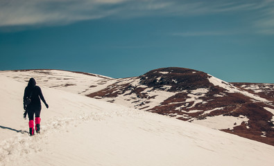 Girl hiking in the snow. Hiking on a sunny day in the Carpathian Mountains in Romania.