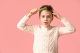 Fototapeta Nowy Jork - Little boy combing hair on color background