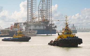 Wall Mural - Tug boats awaiting big cargo ship in harbour for tug assistance, maneuvering, mooring operations. Tugboat and towing service concepts.