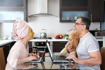 Woman applying facial clay mask. The happy woman and man are working remotely. Concept of the workplace at home, working remotely. Creative.