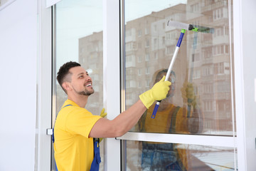 Poster - Professional janitor cleaning window with squeegee indoors