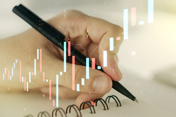 Multi exposure of abstract financial graph with hand writing in notebook on background, financial and trading concept