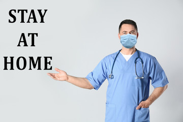 Poster - Doctor in medical mask and text STAY AT HOME on light background