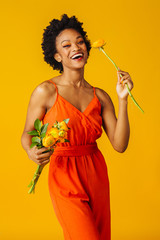 Wall Mural - Portrait of a happy smiling young woman in orange romper and yellow peony bouquet