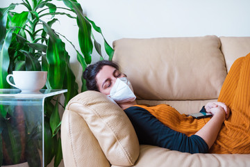 Woman infected with coronavirus disease sleeping in the couch at home. Stay home. Pandemic worldwide virus disease covid 19. Health issues concept. Sick people with face mask to avoid contagious.