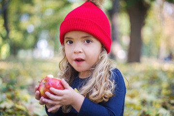 Cute little girl eating an apple in the park