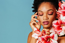 Portrait Of A Beautiful Young Woman With Pink Make Up, Lips, Nail Polish And Amaryllis Flower Blooms Around Face And Eyes Closed