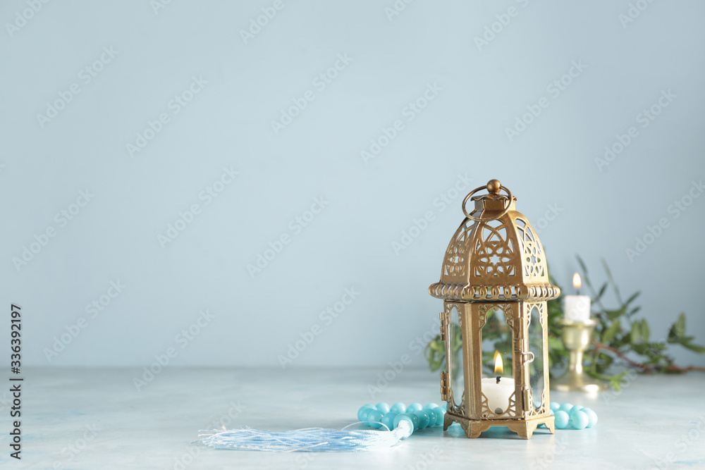 Muslim lamp and tasbih on color background