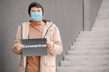Asian Man Wearing Protective Mask On City Street. Concept Of Coronavirus Epidemic