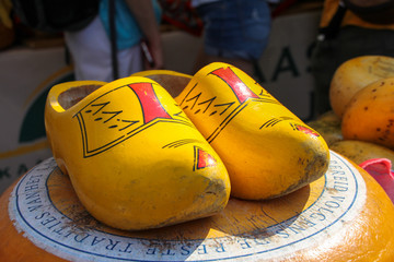 Wall Mural - Yellow and red worn clogs on a wooden cheese