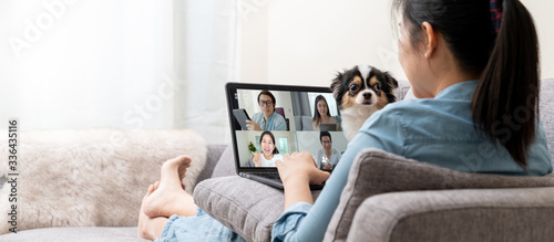 Fotomural Banner of Asian woman on sofa and team on laptop screen talking and discussion in video conference and dog interruption