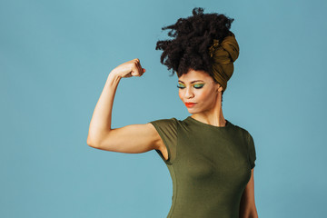 Portrait of a young woman showing her arm and strength and loking down